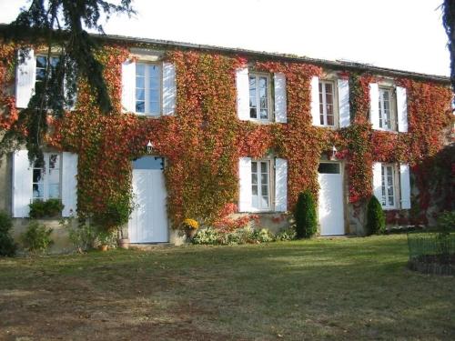 Cette maison recouverte de lierre dispose de portes blanches et de fenêtres blanches. dans l'établissement Chambres d'Hôtes Domaine du Bouchon, à Gans