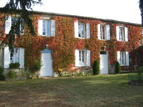 an ivy covered house with white doors and white windows at Chambres d'Hôtes Domaine du Bouchon in Gans