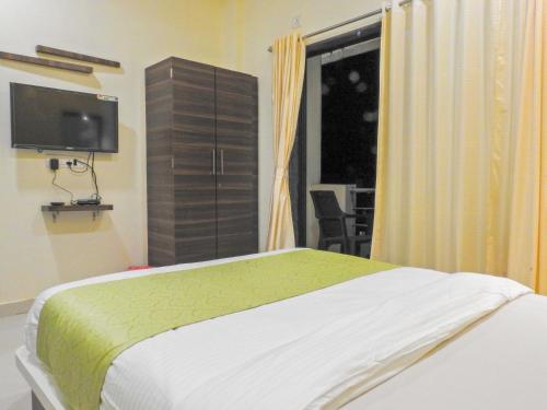 a bedroom with a bed and a flat screen tv at Evergreen Holidays Mahabaleshwar in Mahabaleshwar