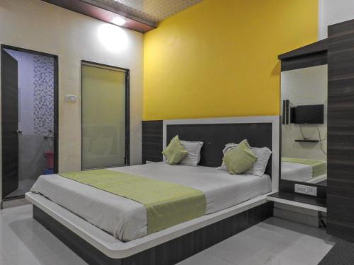a bedroom with a large bed with a yellow wall at Evergreen Holidays Mahabaleshwar in Mahabaleshwar