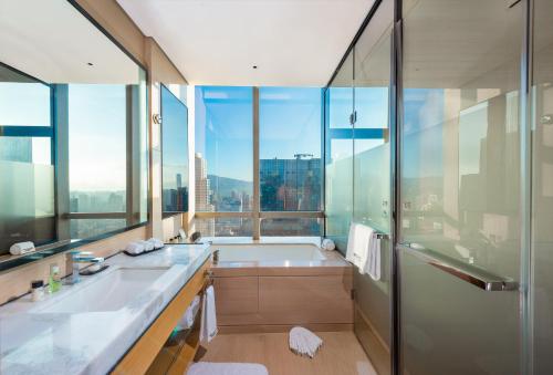 La salle de bains est pourvue d'une baignoire et d'une grande fenêtre. dans l'établissement Shenzhen Futian Wyndham Grand, à Shenzhen