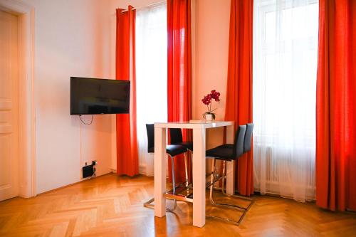 Zimmer mit einem Tisch, einem TV und roten Vorhängen in der Unterkunft Highlight Suite City Center in Wien