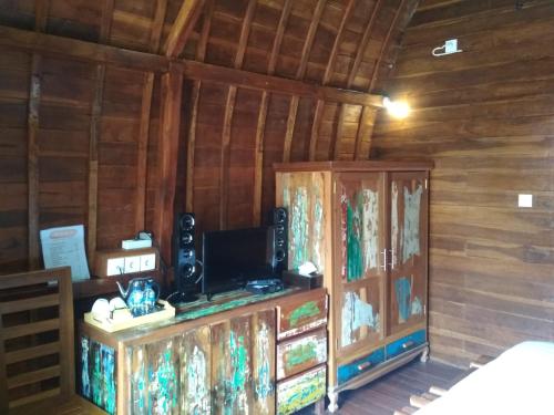 um quarto com uma televisão e uma parede de madeira em Bemo Villas & Pool em Karangasem