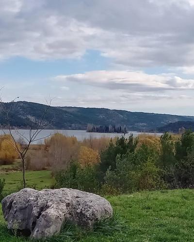 a large rock in a field next to a lake at Krka Fairytale village in Rupe