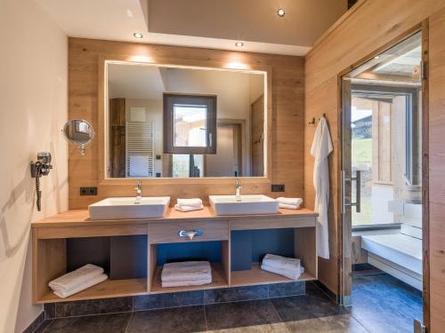 a bathroom with two sinks and a large mirror at Chalets Weitblick Mariasteinerhof in Mariastein