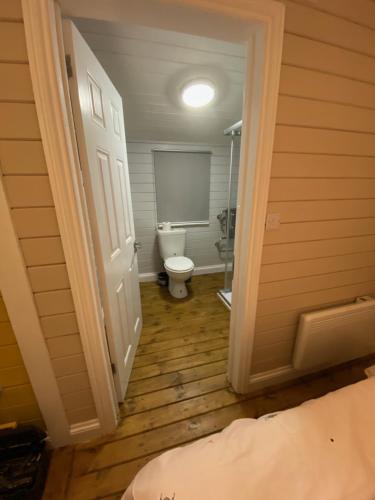 a bathroom with a toilet in a room with a door at Cherry Tree Glamping in Stroud
