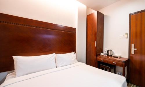 a bedroom with a bed and a wooden headboard at The Quay Hotel West Coast in Singapore
