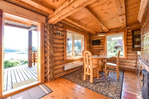 a dining room with a table and chairs in a log cabin at Vila Karališkis in Karališkiai