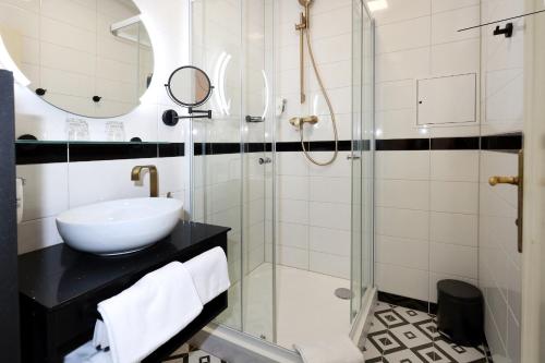 a bathroom with a sink and a glass shower at Art Deco WOLKER by ASTORIA Hotel & Medical Spa in Karlovy Vary