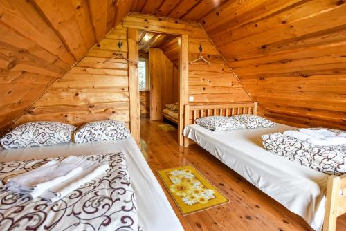 a bedroom with two beds in a log cabin at Vila Karališkis in Karališkiai