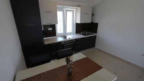 a kitchen with black cabinets and a sink and a window at Apartments Jela in Sveti Vid-Miholjice