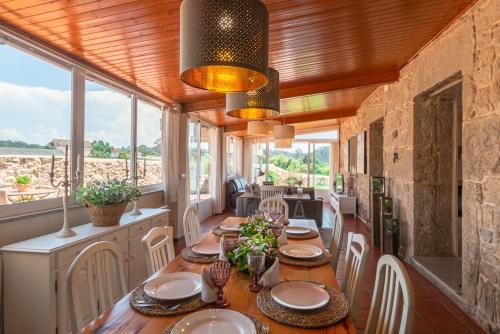 ein Esszimmer mit einem Tisch, Stühlen und Fenstern in der Unterkunft Turismo Casa Benito in Vilanova de Arousa
