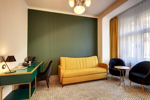 a living room with a yellow chair and a desk at Art Deco WOLKER by ASTORIA Hotel & Medical Spa in Karlovy Vary