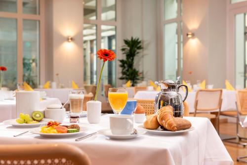 a table with breakfast foods and orange juice on it at Hotel Aquino Berlin in Berlin