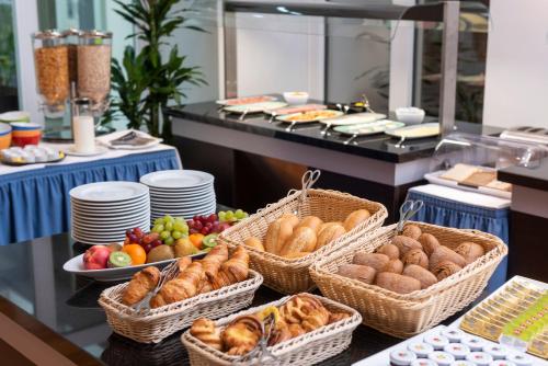 a buffet line with baskets of bread and other foods at Hotel Aquino Berlin in Berlin
