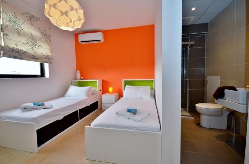 2 camas en una habitación con pared de color naranja en City Living Suite Tk 3 Rm 1, en San Julián