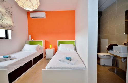 2 camas en una habitación con pared de color naranja en City Living Suite Tk 3 Rm 1, en San Julián