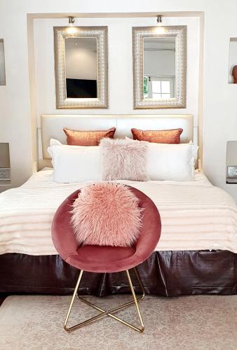 a bedroom with a large bed with a red chair at De Kloof Heritage Estate and Wellness in Swellendam