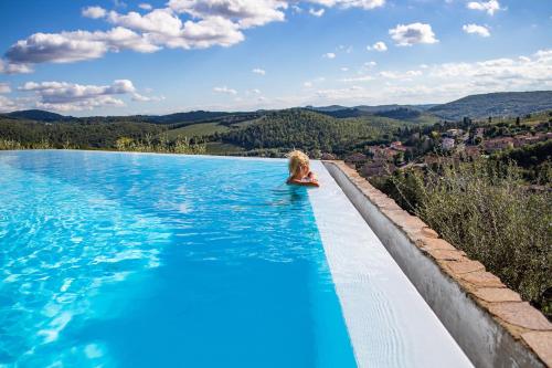 a woman sitting in a swimming pool with a view at Capannelle Wine Resort in Gaiole in Chianti
