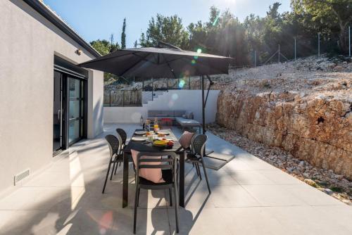 a table and chairs with an umbrella on a patio at Swedish-Style Villa Salz in Fiskardho