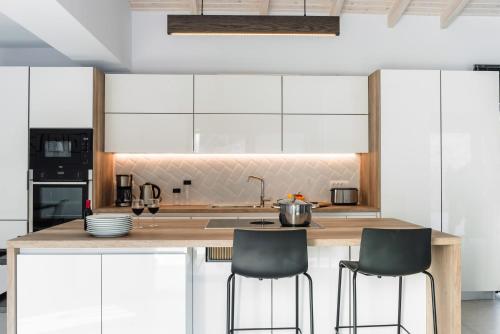 a kitchen with white cabinets and bar stools at Swedish-Style Villa Salz in Fiskardho