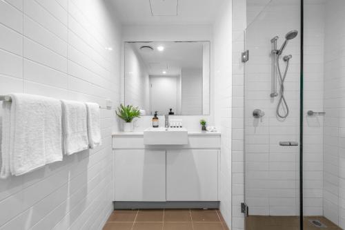 a white bathroom with a sink and a mirror at Waterloo St Apartments by Urban Rest in Sydney