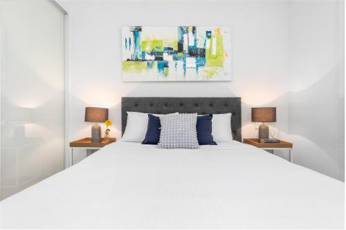 una camera da letto con un grande letto bianco con due comodini di Waterloo St Apartments by Urban Rest a Sydney
