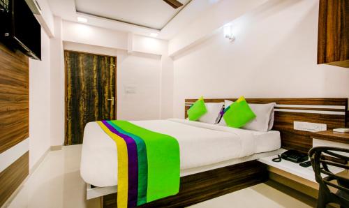 a bedroom with a large white bed with green accents at Treebo Kings Inn Vashi in Mumbai