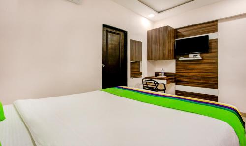 a bedroom with a white bed and a flat screen tv at Treebo Kings Inn Vashi in Mumbai