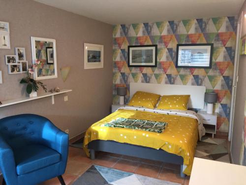 ein Schlafzimmer mit einem Bett und einem blauen Stuhl in der Unterkunft La Ferme de Kérivoas in Audierne