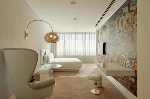 a bedroom with a bed and a large painting on the wall at Mondrian Doha in Doha