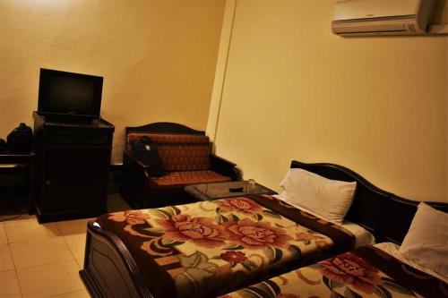 a bedroom with a bed and a chair and a television at Suvastu Resort in Swat