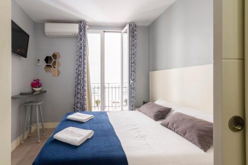 Un dormitorio con una gran cama blanca con sábanas azules y una ventana en 8Rooms Madrid, en Madrid