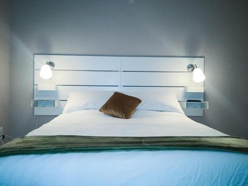 een slaapkamer met een groot wit bed en 2 verlichting bij La casa di Fabia - Home suite in Messina