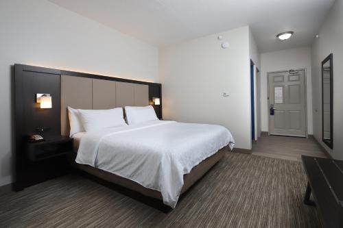 a bedroom with a large white bed and a door at Holiday Inn Express Grand Rapids Southwest by IHG in Grandville