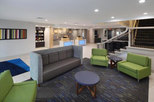 a lobby with a couch and chairs and stairs at Holiday Inn Express Grand Rapids Southwest by IHG in Grandville
