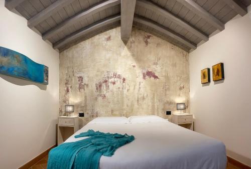 ピエトラサンタにあるDimora Carducciの白いベッドと壁が備わるベッドルーム1室が備わります。