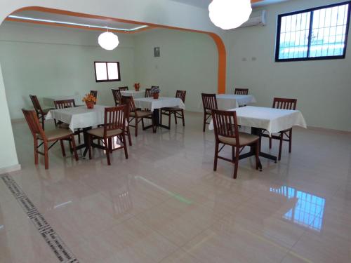 a dining room with white tables and wooden chairs at Hotel Renacer in Santo Domingo