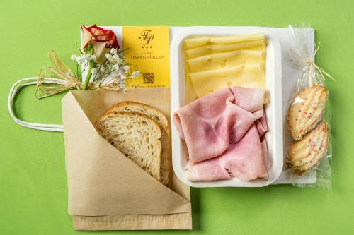 a lunch box with a sandwich and a bag of cheese at Hotel Tempio Di Pallade in Rome