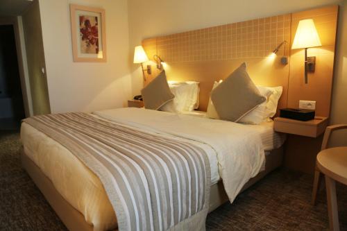 a hotel room with a large bed with pillows at Concorde Sfax Centre in Sfax