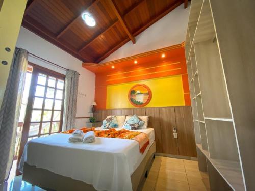 a bedroom with a large bed with an orange wall at Pousada Arquipélago in Florianópolis