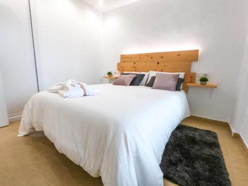 a bedroom with a large white bed with a wooden headboard at Apartamento Altea Blanca in Altea