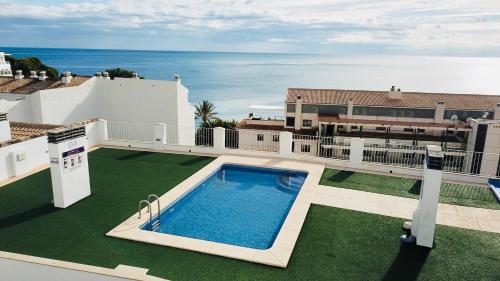 a swimming pool on the roof of a house with the ocean at Apartamento Altea Blanca in Altea
