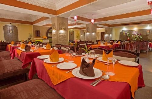 a restaurant with long tables with red table cloths at Hotel Rajmahal in Guwahati