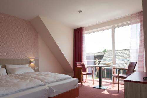 a hotel room with a bed and a table with chairs at AS Feriendorf in Wangerland