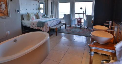 a bathroom with a bath tub and a bed at On the Beach Guesthouse Jeffreys Bay in Jeffreys Bay