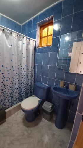 a blue tiled bathroom with a toilet and a sink at La Tribu del Indio in San Pedro de Atacama