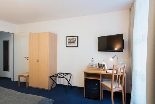 a hotel room with a desk and a tv on the wall at City Apart Hotel in Düsseldorf