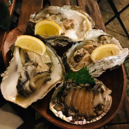 three oysters on a wooden plate with lemon slices at Guest house & Bar Diamond Head in Mihana