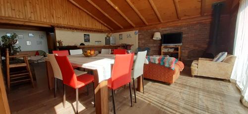 a dining room with a table and red chairs at Casa Amanecer Vichuquén in Lago Vichuquen